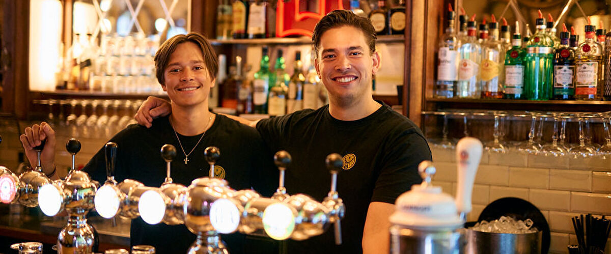 Twee barmannen lachend achter de tapkranen